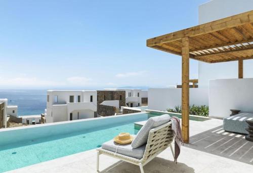 a villa with a swimming pool and a chair at LYO II Boutique Suites in Mikonos
