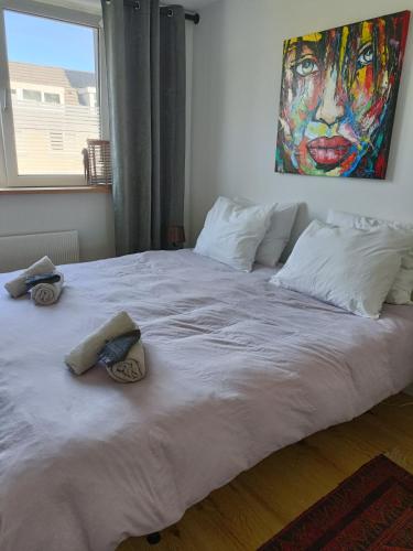 a large white bed with two pillows and a painting at B&B Het Heusje in Zaandam