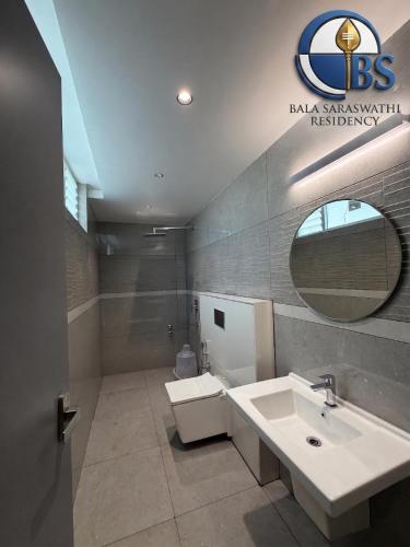 a bathroom with a sink and a toilet and a mirror at Bala Saraswathi Residency in Tuticorin