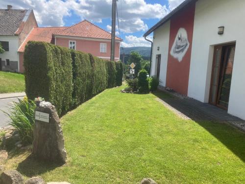 a yard with a hedge in front of a house at Kašperky Apartmány in Kašperské Hory