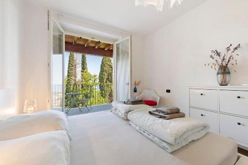 a white bedroom with three beds and a balcony at Casa 3 Rose Lake View and Pool in Toscolano Maderno