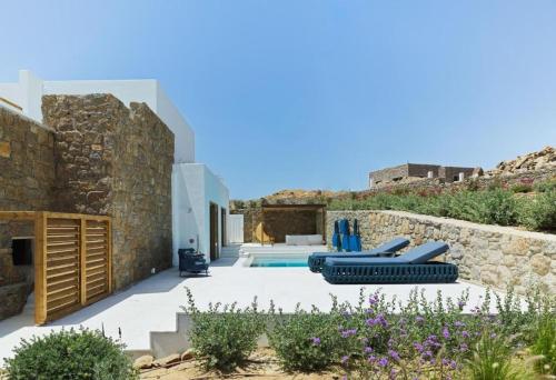 a villa with a pool and a stone wall at LYO II Boutique Suites in Mikonos
