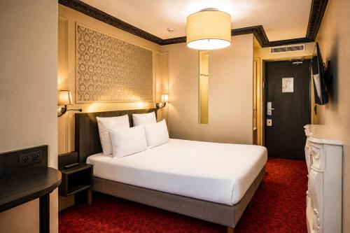 a hotel room with a white bed and a television at Hôtel Le Montmartre Saint Pierre in Paris