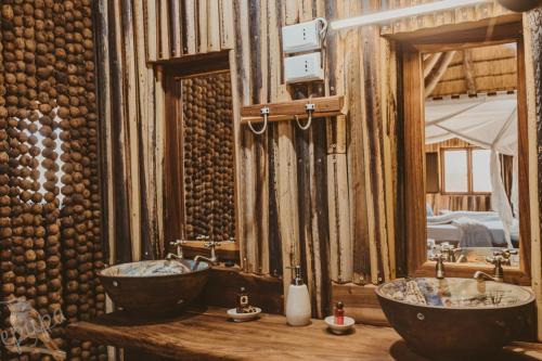 a bathroom with two sinks and two mirrors at Epupa Falls Lodge in Epupa