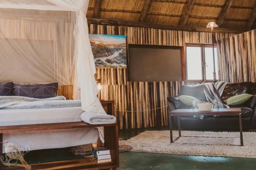 a bedroom with a bed and a flat screen tv at Epupa Falls Lodge in Epupa