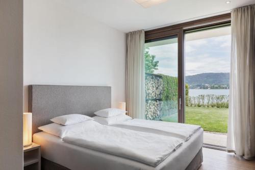 a bedroom with a bed and a large window at Linde Villas in Maria Wörth