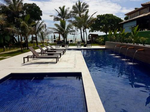 a swimming pool with lounge chairs and palm trees at Ravenala Hotel in Arraial d'Ajuda