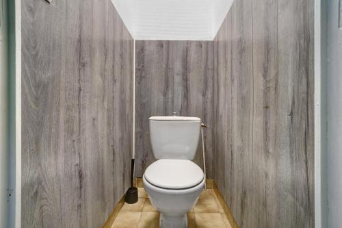 a white toilet in a bathroom with wooden walls at 11.Les tilleuls option Clim -6 pers in Calviac