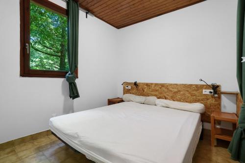 a bedroom with a white bed and a window at 11.Les tilleuls option Clim -6 pers in Calviac