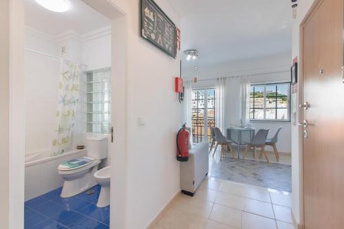a bathroom with a toilet and a table with chairs at Casa Lori Albufeira in Albufeira
