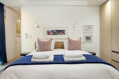 a bedroom with a large white bed with two pillows at 17 Marine - Apt 103 - Private Hot Tub & Garden in Hermanus