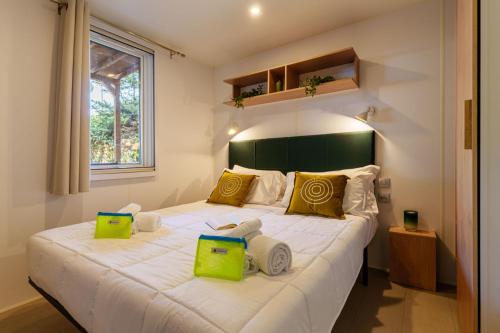 a bedroom with a large white bed with green accents at Club del Sole Le Gorette Cecina Easy Camping Village in Marina di Cecina