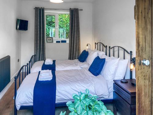 a bedroom with a bed with blue pillows at Abbey Cottage in St Bees