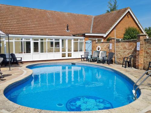 a swimming pool with blue water in front of a house at The Nest in Aylsham