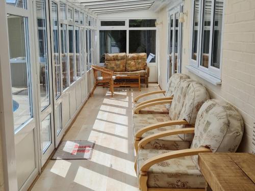 a porch with chairs and a table and windows at The Nest in Aylsham