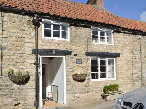 a stone house with a white door and two windows at Toad Hall in Helmsley
