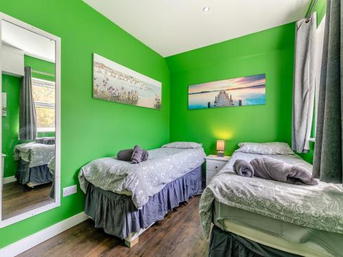 a green room with two beds and a mirror at By The Beach- Uk31201 in Downderry