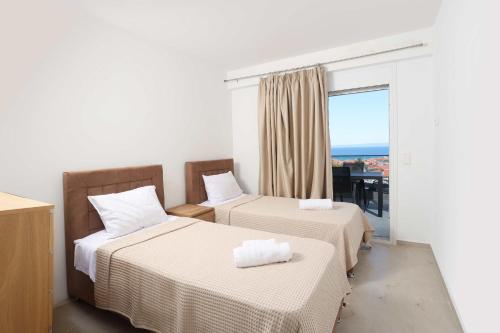 two beds in a room with a window at Local View Apartments in Polychrono