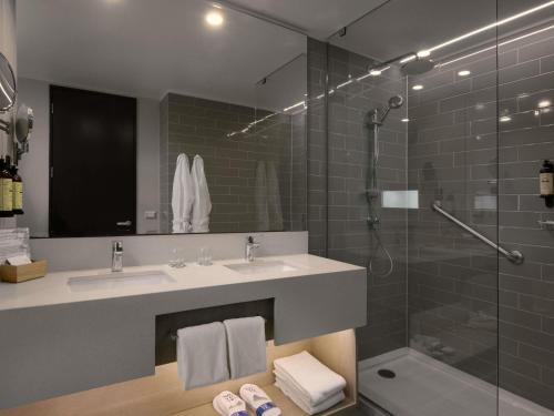 a bathroom with a sink and a glass shower at Novotel Arica in Arica
