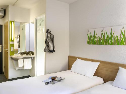 a bedroom with two beds and a sink and a mirror at IBIS BUDGET CAPAO Bonito in Capão Bonito