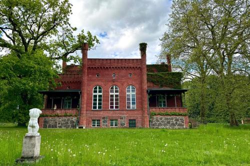 a red brick house with a statue in front of it at Herrenhaus Libnow in Murchin
