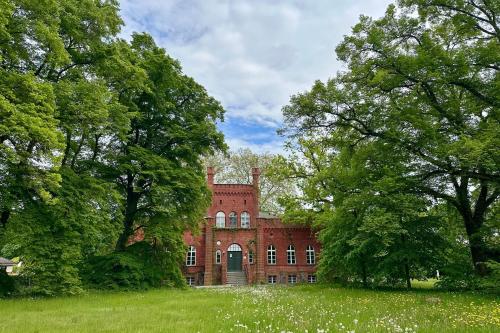 an old red brick house with trees in front of it at Herrenhaus Libnow in Murchin