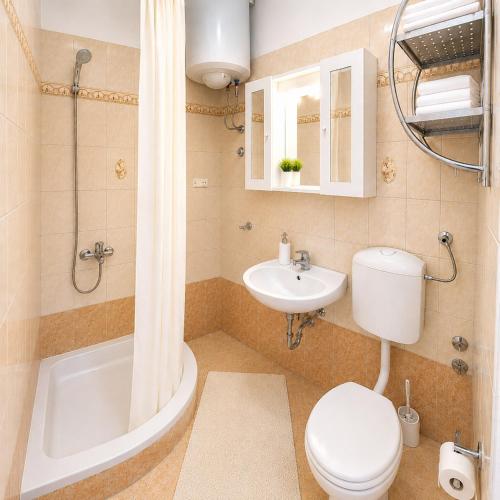 a bathroom with a toilet and a sink and a tub at Apartments Mohar III in Baška
