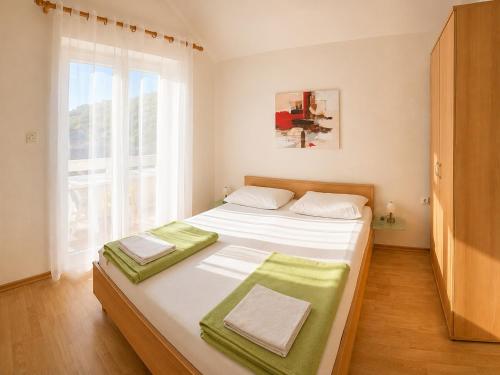 a bedroom with a bed with white sheets and a window at Apartments Mohar III in Baška