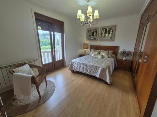a bedroom with a bed and a chair and a window at Casa da Xoiña in Foz