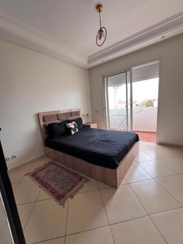 a bedroom with a large bed with a black blanket at Garden Beach 2 in Sidi Rahal