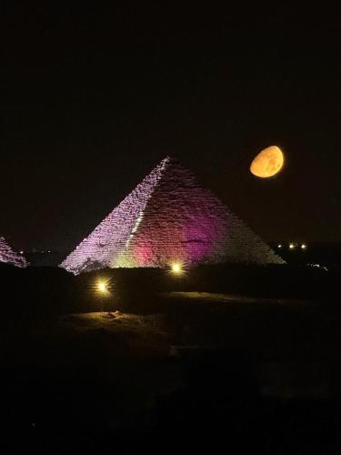 an image of the pyramids at night with a moon at Aziz Egypt Hotel in Cairo