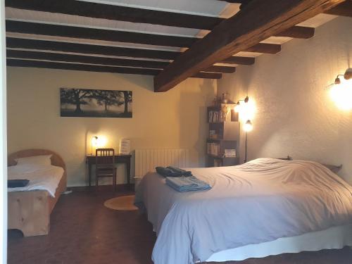 a bedroom with two beds and a table with a chair at Le Moulin du Châtelier in Paulmy