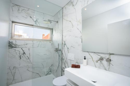 a white bathroom with a shower and a sink at Villa Bazaruto in Lagos