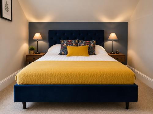 a bed with a blue headboard and a yellow pillow at The Godwins in Hereford