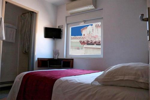 a bedroom with a large bed with a window at Hôtel des ARTS Aix in Aix-en-Provence