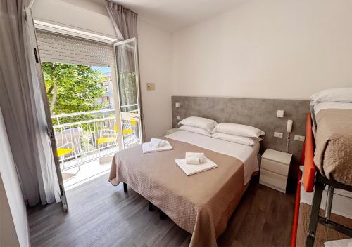 a bedroom with two beds and a large window at Hotel Ariva in Rimini