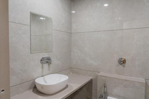 a white bathroom with a sink and a mirror at Hotel Rangoli - 10 min from Palsana chowk in Navsāri