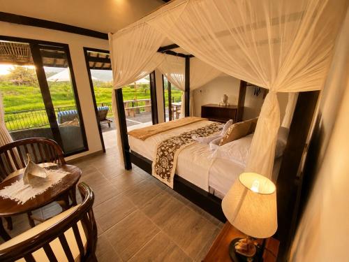 a bedroom with a canopy bed and a table and a chair at The Kubu Sidemen 2 in Silebeng