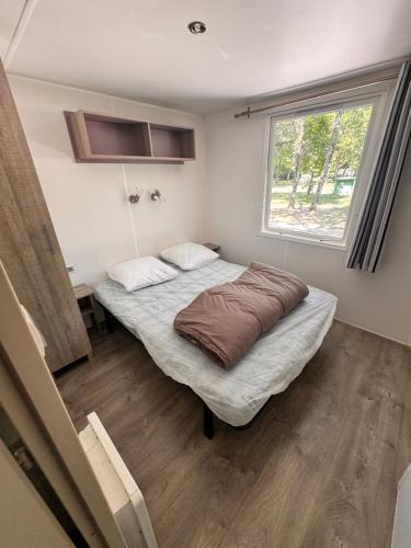 a small bedroom with a bed and a window at Camping les sablons in Vergeroux