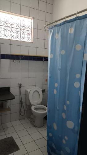 a bathroom with a toilet and a blue shower curtain at Hostel Republika in Natal