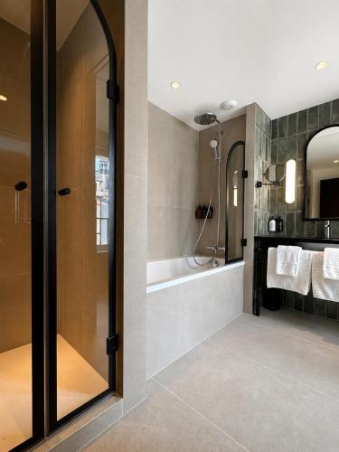 a bathroom with a shower and a tub and a sink at Hotel Grand Coeur Latin in Paris