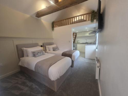 a bedroom with two beds and a kitchen in the background at The Loft Studio Westbury in Westbury
