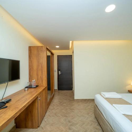 a hotel room with a bed and a flat screen tv at The Clock Tower Inn in Bangalore