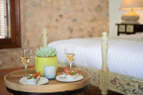 a table with two glasses of wine on a bed at Casa Font i Roig in Maria de la Salut