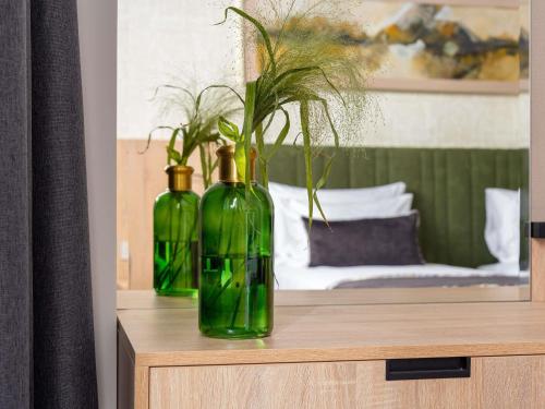 two green bottles sitting on top of a table at Mercure Conacul Cozieni in Bucharest