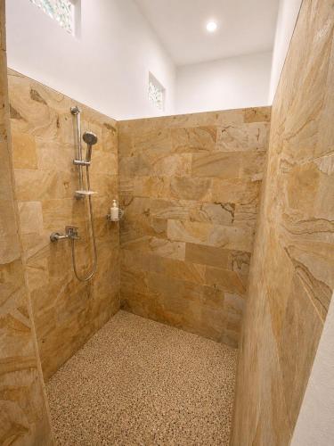 a bathroom with a shower with a stone wall at The Kubu Sidemen 2 in Silebeng