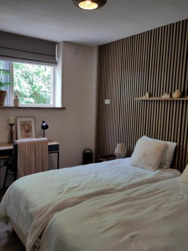 a bedroom with a bed and a desk and a window at HotelPension van Ewijcksluis in Anna Paulowna