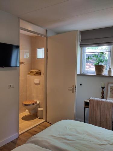 a bedroom with a bathroom with a toilet and a window at HotelPension van Ewijcksluis in Anna Paulowna