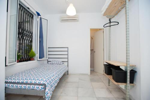 1 dormitorio con cama, escritorio y ventana en La Central Sevilla, en Sevilla