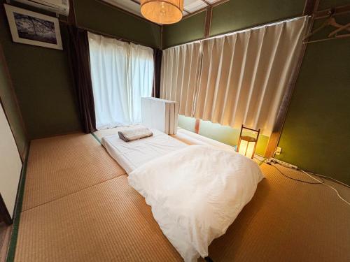 a bedroom with a bed in a room with a window at 古民家宿Step inn Hagi なかつえ in Hagi
